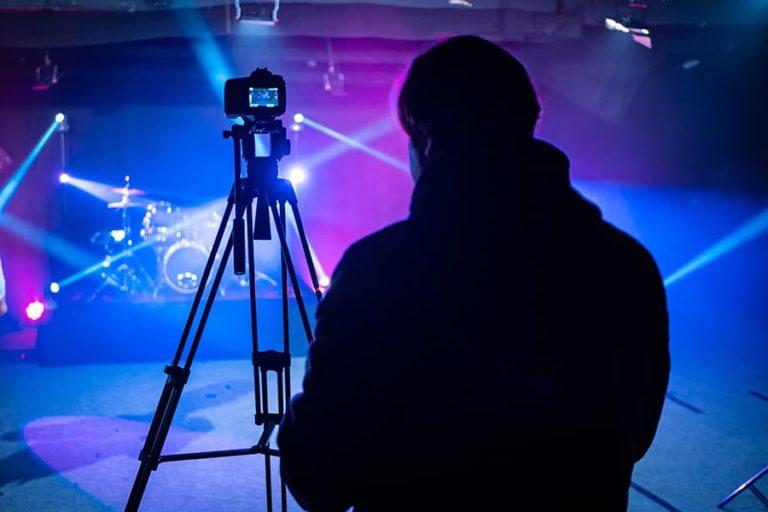 一名摄像师正在安装他的摄像机和录像设备，准备记录一场音乐会.